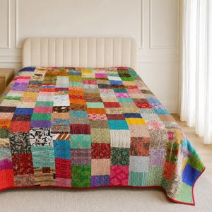 May include: A rectangular quilt featuring a patchwork design composed of numerous small, square fabric pieces in a wide variety of colours, including red, blue, green, yellow, pink, and orange, with diverse floral, geometric, and paisley patterns.