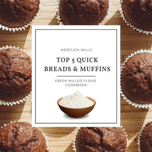 May include: A cookbook cover with the title "Top 5 Quick Breads & Muffins" by "Mertilich Mills" with a bowl of white flour on a wooden background with chocolate muffins.