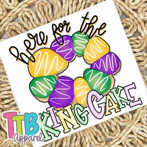 May include: White t-shirt with a colorful graphic of a King Cake, featuring yellow, green, and purple icing. The text "Here for the King Cake" is written above the cake in black script. The words "TTB Apparel" are in the bottom left corner.