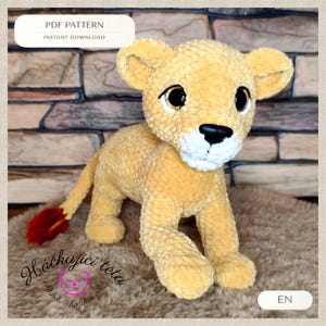 May include: A plush, golden-yellow lion cub with large, expressive eyes and a black nose. The lion has a fluffy mane and a red-tipped tail. The image includes the text "PDF PATTERN" and "INSTANT DOWNLOAD".