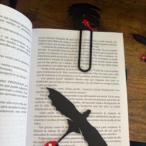 May include: Black metal bookmark featuring a dragon design with red accents, placed in an open book. The bookmark is a decorative accessory for readers, adding a touch of fantasy to the reading experience.