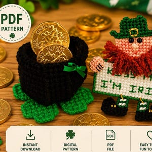 May include: A St. Patrick's Day craft project showing a black pot filled with gold coins and a leprechaun holding a sign saying "Kiss Me I'm Irish." The leprechaun has a green hat and red beard. Green shamrocks are also present.