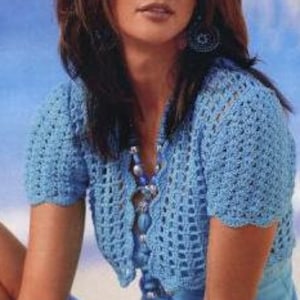 Op de afbeelding: Een lichtblauw gehaakt topje met korte mouwen en een gegolfde zoom.