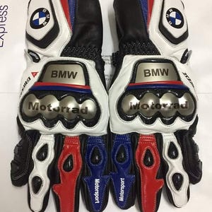 May include: A pair of white, black, red and blue leather motorcycle gloves with the BMW logo and the text "BMW Motorrad Motorsport" on them.