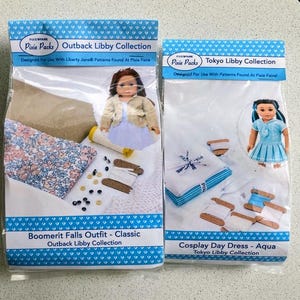 May include: Two clear plastic packages of doll clothing kits. The "Boomerit Falls Outfit" kit includes fabric, buttons, and thread. The "Cosplay Day Dress" kit includes fabric and thread. Both kits feature doll images and text.