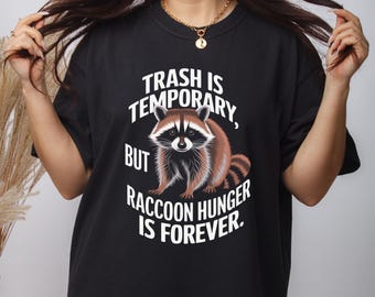 Könnte beinhalten: Schwarzes T-Shirt mit einem Waschbär-Motiv und dem Text "Trash is temporary, but raccoon hunger is forever."
