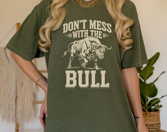 May include: A moss green t-shirt with a white graphic of a bull and the text "Don't mess with the bull".