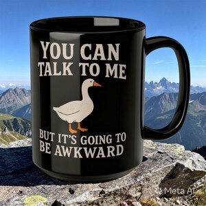 May include: A black ceramic mug featuring a white goose illustration in the center. The text printed in white reads: YOU CAN TALK TO ME BUT IT'S GOING TO BE AWKWARD. The mug has a curved handle on the right side and a smooth, glossy finish throughout.