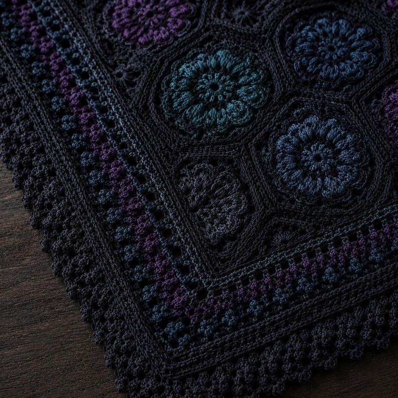 May include: A dark-toned crochet blanket featuring a repeating pattern of hexagonal motifs with intricate floral centers in shades of deep blue, teal, and purple. The edges are finished with a textured, scalloped border in a solid dark charcoal.