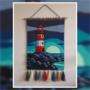 Puede incluir: Tapiz de pared tejido que representa un faro rojo y blanco, con una luz brillante. La escena incluye un cielo azul oscuro, un mar turquesa y un gran sol. La parte inferior tiene borlas coloridas.