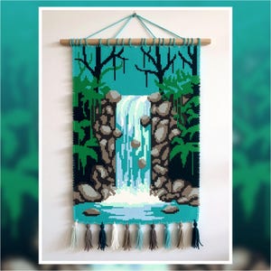 Puede incluir: Un tapiz de pared hecho a mano que representa una escena de cascada. La obra de arte presenta un fondo turquesa con una cascada que cae entre acantilados rocosos. El follaje verde y los árboles enmarcan la cascada. El borde inferior tiene borlas decorativas en varios colores.