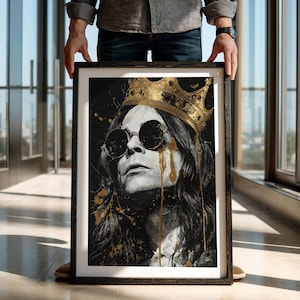 Könnte beinhalten: Gerahmter Kunstdruck mit einem Schwarz-Weiß-Porträt einer Person mit runder Sonnenbrille und goldener Krone. Goldene Farbe tropft das Gesicht hinunter, vor einem schwarzen Hintergrund. Das Kunstwerk wird in einem schwarzen Rahmen präsentiert.