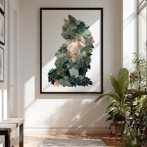 Op de afbeelding: Een ingelijste kunstdruk met een gestileerde kat samengesteld uit bladeren en bladeren in groen, roze en wit. Het kunstwerk staat tegen een witte achtergrond en is zwart omlijst. De print wordt tentoongesteld in een hal met een bank en planten.