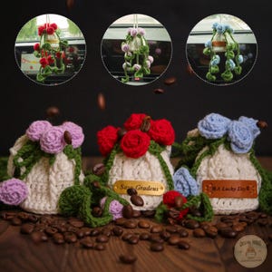 May include: Crocheted hanging flower pot with red, purple, and blue flowers. The white pot has green vines and is filled with coffee beans. The text on the tag reads "Sara Gradeus" and "A Lucky Day".