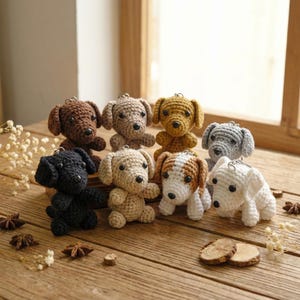 May include: A collection of handmade crochet dog keychains in various colors, including brown, tan, black, and white. Each dog has a small metal ring for attaching to keys or bags. The dogs are arranged on a wooden surface.