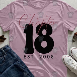 Peut inclure: T-shirt rose clair avec l'inscription "Chapter 18" en écriture cursive et le chiffre "18" en noir gras. En dessous, "EST. 2008". Le t-shirt est associé à un jean bleu et des baskets blanches.