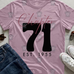 Puede incluir: Camiseta rosa claro con la frase "Chapter 71" en cursiva y el número 71 en negro. Debajo, "EST. 1955". La camiseta se muestra con vaqueros azules y zapatillas blancas.