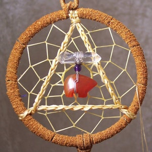 May include: A brown leather dreamcatcher with a white and yellow web, a clear quartz crystal, a purple bead, and a red carnelian bear charm.