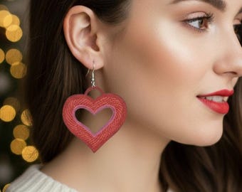 Pode incluir: Brincos vermelhos em forma de coração com um coração interior rosa mais claro. Os brincos estão pendurados em ganchos prateados. Um acessório festivo, perfeito para o Dia dos Namorados ou qualquer ocasião.