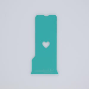 May include: A teal-colored phone screen protector with a heart-shaped cutout. The protector has a rectangular shape with a notch at the top and the text "smashed" at the bottom. The background is plain white.