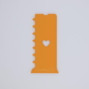 May include: Orange plastic phone case with a heart-shaped cutout and a jagged edge. The case has the text "smashed it!" at the bottom. The case is designed to protect a phone.