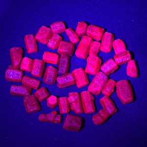 Peut inclure: Une collection de pierres précieuses rubis brutes et non taillées. Les rubis sont d'une couleur rouge vif et semblent être éclairés par une source de lumière vive. Les pierres précieuses sont dispersées sur une surface bleu foncé.