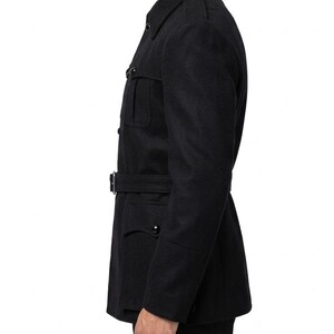 May include: A black wool coat with a belted waist and multiple pockets. The coat has a classic military-inspired design with a button-up front and a notched collar. The sleeves have buttoned cuffs. The coat is a solid black color.