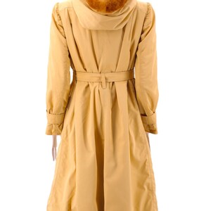 May include: A long, yellow raincoat with a fur-lined hood and a belt. The coat has a fitted waist and a flared skirt.