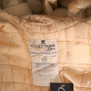 May include: A beige quilted jacket with a fur collar. The label reads "Courreges Paris Couture Future Made in France" and includes fabric content information.