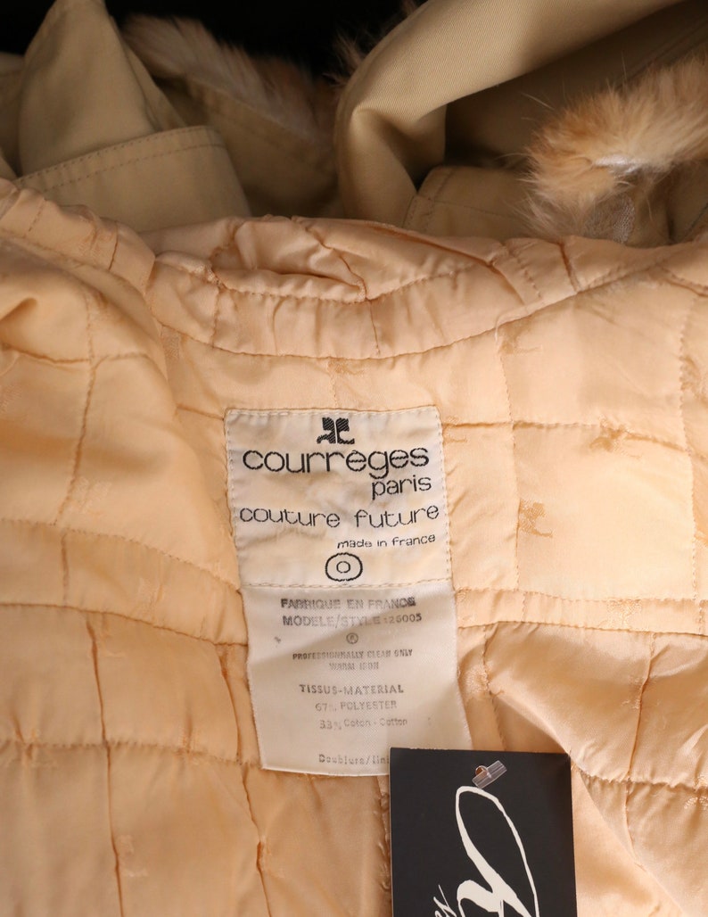 May include: A beige quilted jacket with a fur collar. The label reads "Courreges Paris Couture Future Made in France" and includes fabric content information.