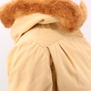 May include: A beige hooded jacket with a brown faux fur trim around the hood.