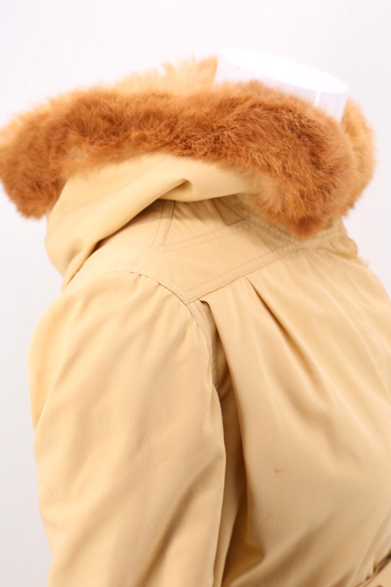 May include: A beige hooded jacket with a brown faux fur trim around the hood.