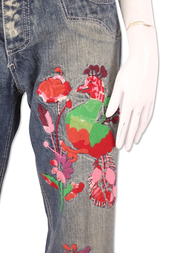 Parrot faded jeans with embroidered flower knee patches photographed on a  white background Stock Photo - Alamy