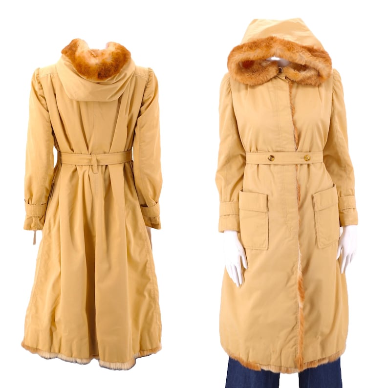 May include: A long, tan, hooded coat with a fur trim around the hood and hem. The coat has a belt and two pockets.