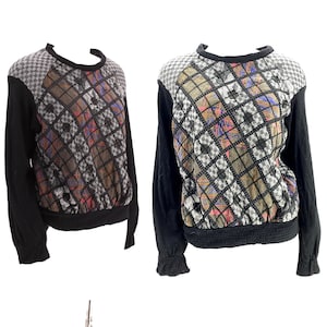 May include: Two long-sleeved sweaters. The sweaters have black sleeves and a black, ribbed hem. The upper chest and shoulder area is a gray and white checkered pattern. The center panel has a diamond pattern with brown, pink, and blue accents.