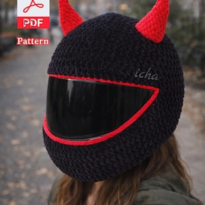 Puede incluir: Funda de casco negra de ganchillo con ribete y cuernos rojos. El casco tiene una visera oscura y la palabra "icha" está escrita en el lateral. Un icono de patrón PDF está en la esquina superior izquierda.
