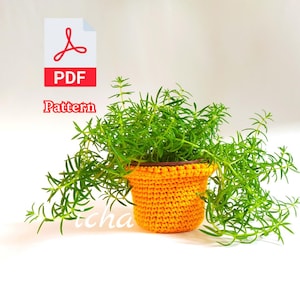May include: A vibrant green plant in a bright orange crocheted pot. The pot has a brown rim and is filled with lush, trailing greenery. The image includes a PDF pattern icon and the word "Pattern".