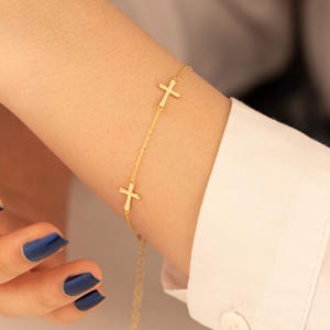 May include: A gold chain bracelet with three small cross charms.