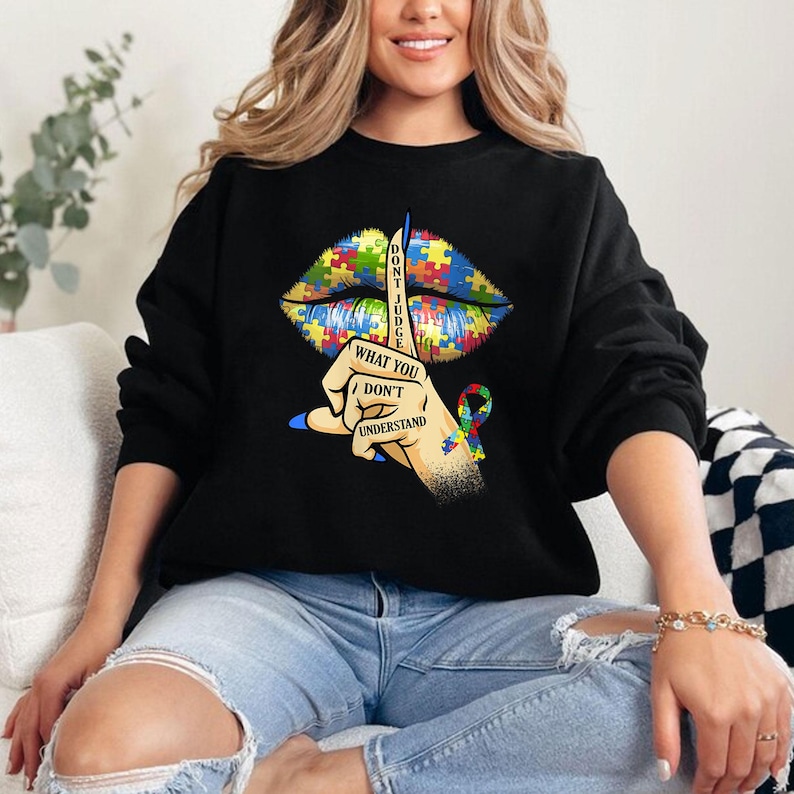 May include: Black sweatshirt with a graphic of a puzzle piece lips with a finger over them and the text "Don't Judge What You Don't Understand".