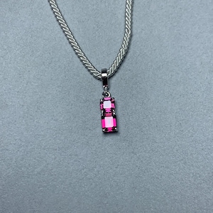 May include: A silver necklace with a pendant featuring two rectangular, hot pink gemstones. The gemstones are set in a silver frame and are connected vertically. The chain is a silver curb chain.