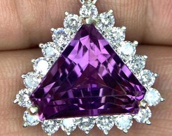 May include: A triangular amethyst pendant with a silver setting and a halo of small round diamonds.
