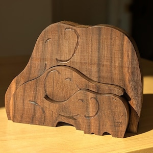 May include: A set of three wooden elephants, carved in a nested design. The elephants are made of dark brown wood and have a smooth, polished finish.