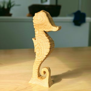 May include: A wooden seahorse figurine with a light brown color and a detailed, textured surface.