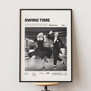 Puede incluir: Póster enmarcado en blanco y negro con el título de la película "SWING TIME" en la parte superior. La imagen muestra a una pareja bailando con ropa formal. El póster se exhibe sobre un taburete de madera contra una pared blanca.