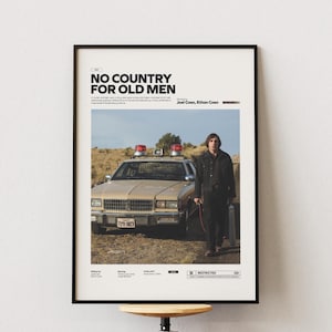 Könnte beinhalten: Gerahmtes Filmplakat für "No Country for Old Men" mit einem beigefarbenen Polizeiauto mit roten Lichtern und einem Mann in einer schwarzen Jacke. Das Plakat hat den Filmtitel oben und ist vor einem neutralen Hintergrund.