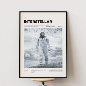 Può includere: Poster incorniciato con il film "Interstellar". Il poster mostra una persona in tuta spaziale in un paesaggio innevato. Il titolo è in alto, con il nome del regista sotto. Il poster è in una cornice nera.