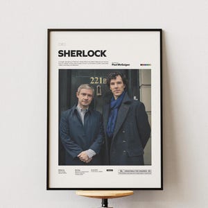May include: A black and white poster with the title "SHERLOCK" in bold white text. The poster features two men in suits standing in front of a building with the number "221B" on the door. The poster is for the BBC television series "Sherlock".