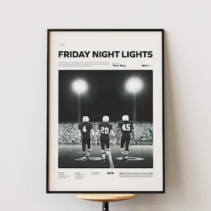 May include: Black and white framed poster featuring the text "FRIDAY NIGHT LIGHTS" above an image of three football players walking onto a field. The players wear jerseys numbered 4, 20, and 45. The poster is displayed on a white wall.
