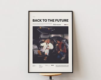 May include: Framed poster featuring the movie "Back to the Future." The poster has a black frame and displays a scene with two characters and a DeLorean car. The title and credits are at the top, with additional text at the bottom.