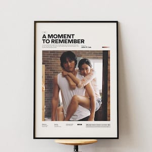 May include: A movie poster for the film "A Moment to Remember" starring John H. Lee. The poster features a black and white photo of a man and woman embracing.